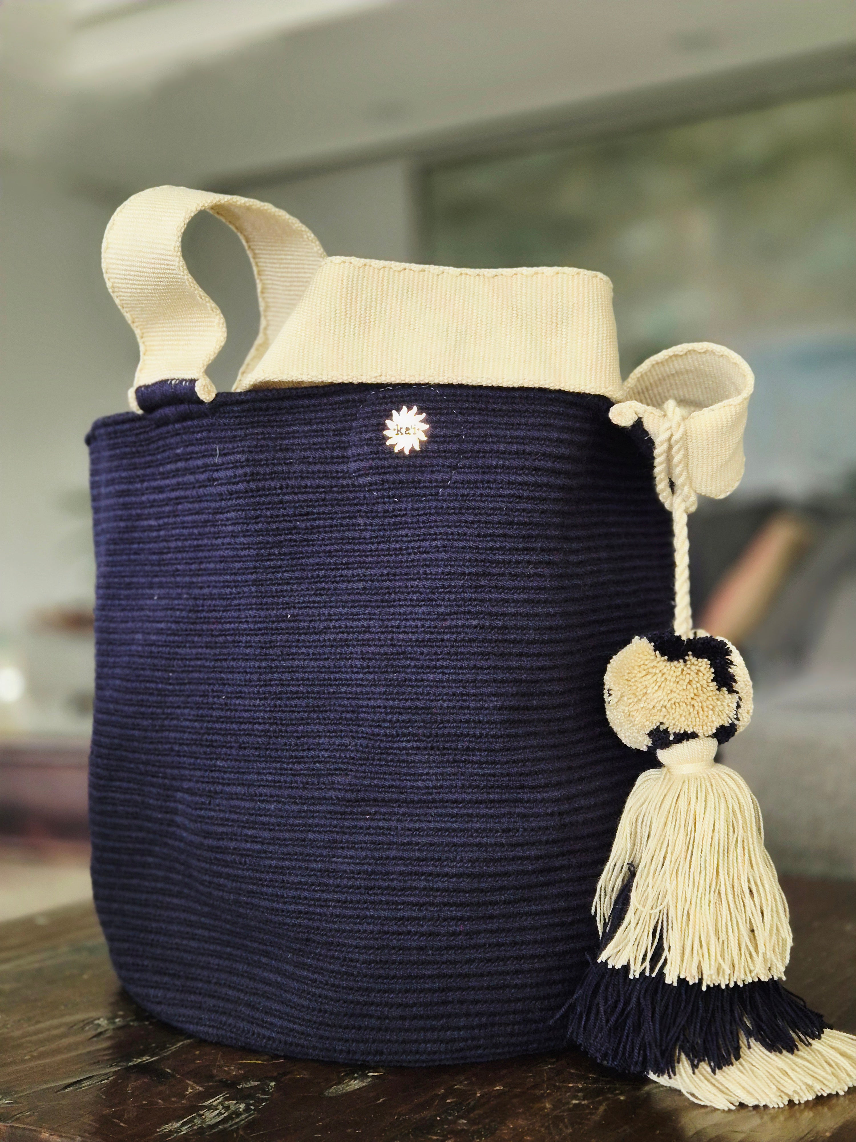 Cartera azul marino con asa beige y pompón azul y beige