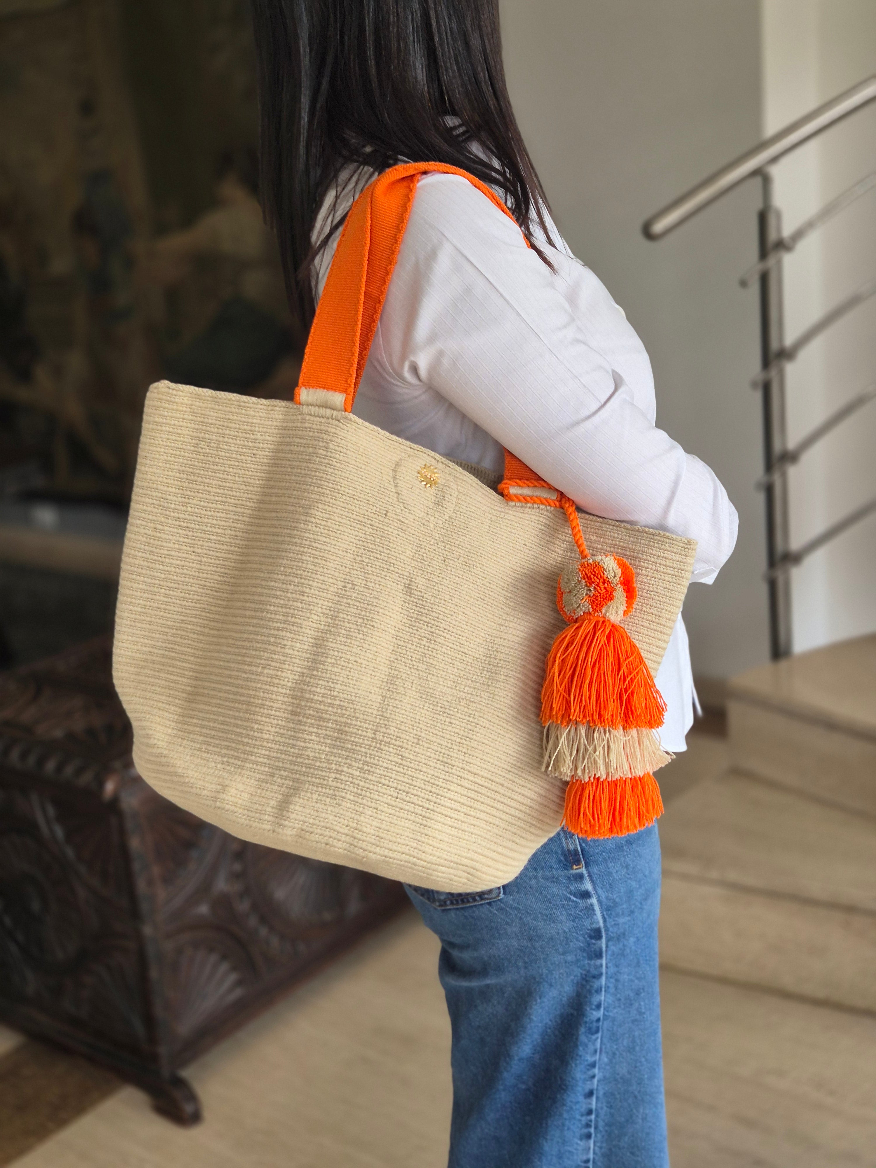 Beige handbag with orange handle and orange and beige pompom