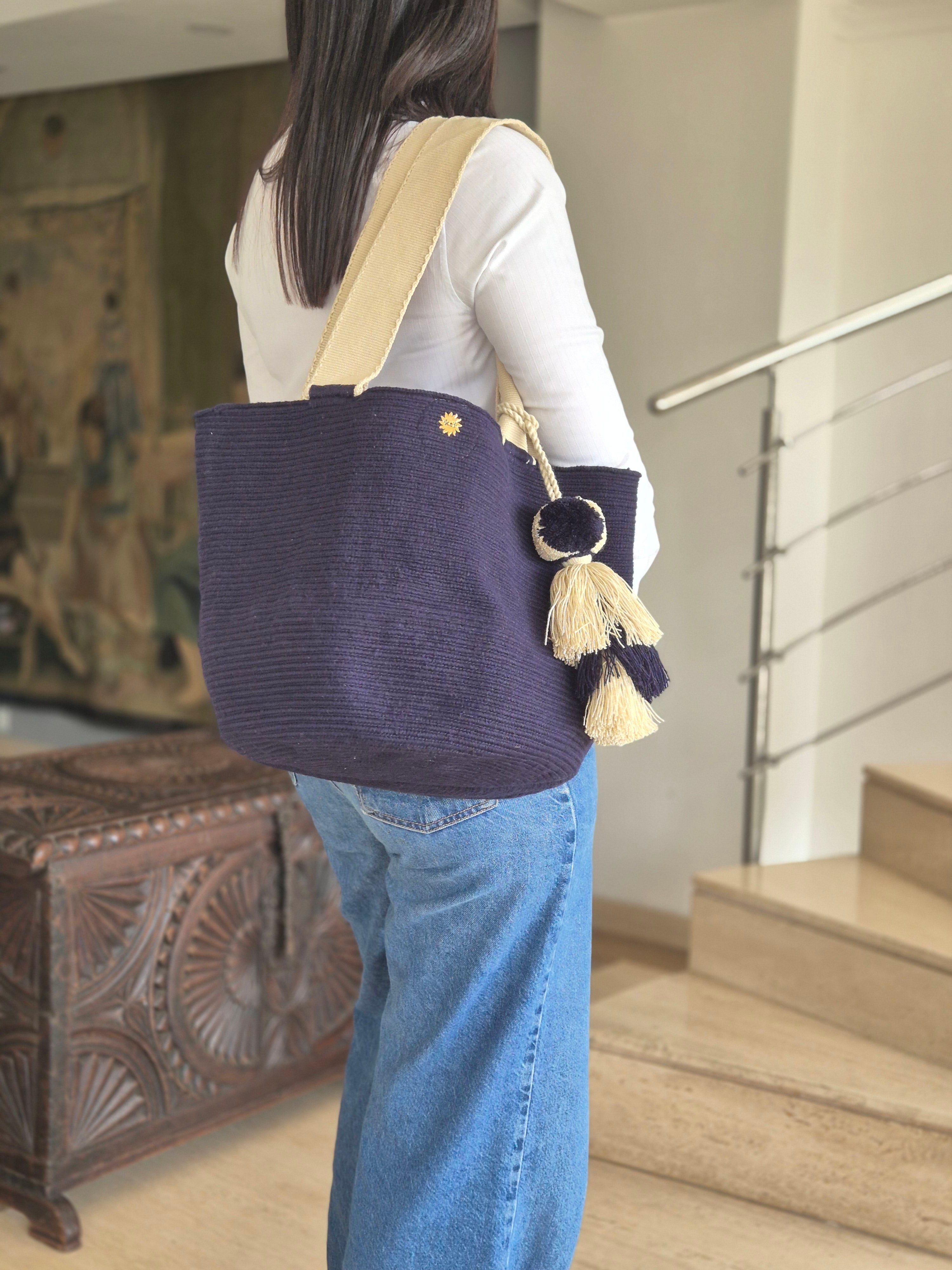 Cartera azul marino con asa beige y pompón azul y beige