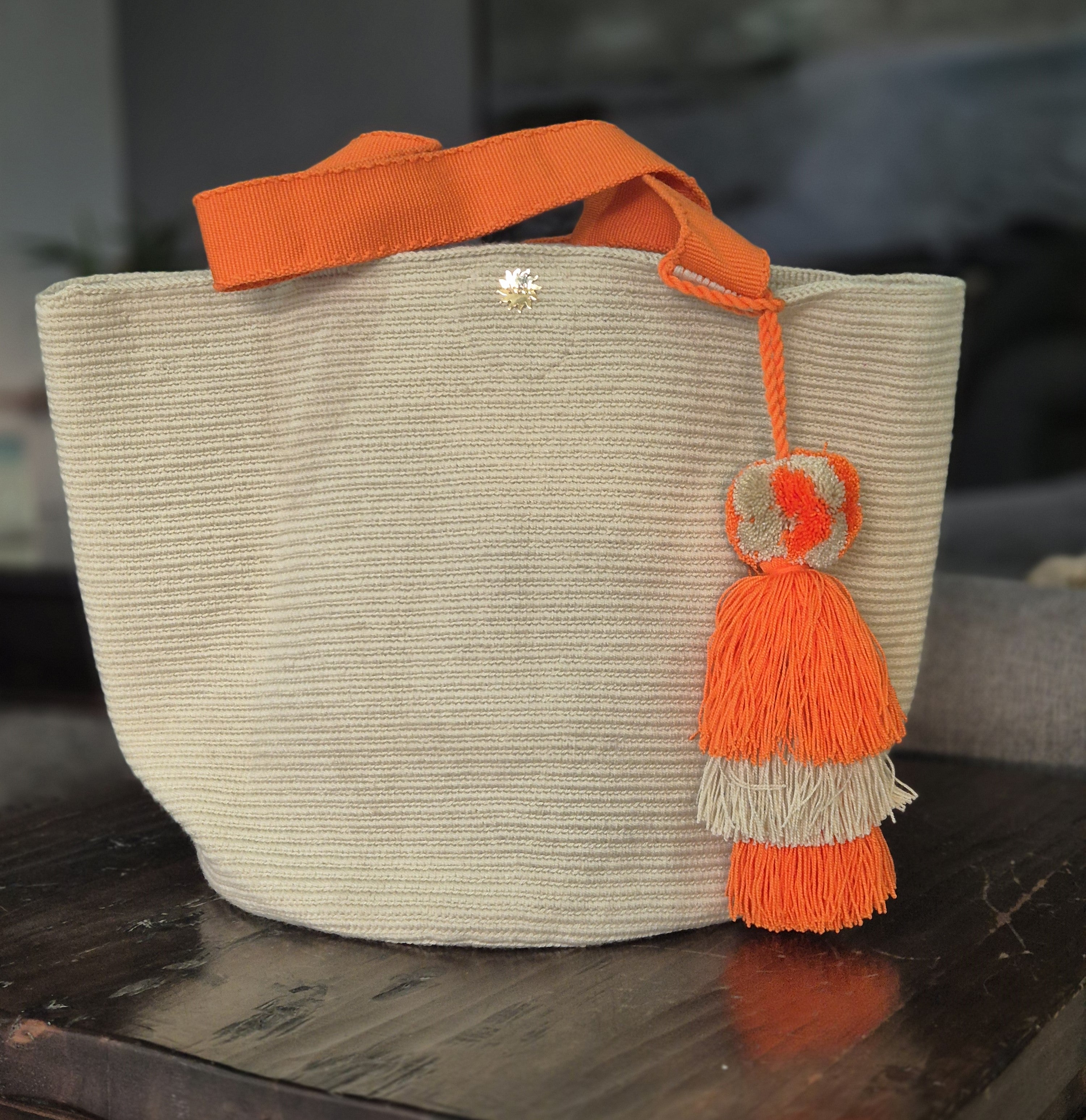 Beige handbag with orange handle and orange and beige pompom