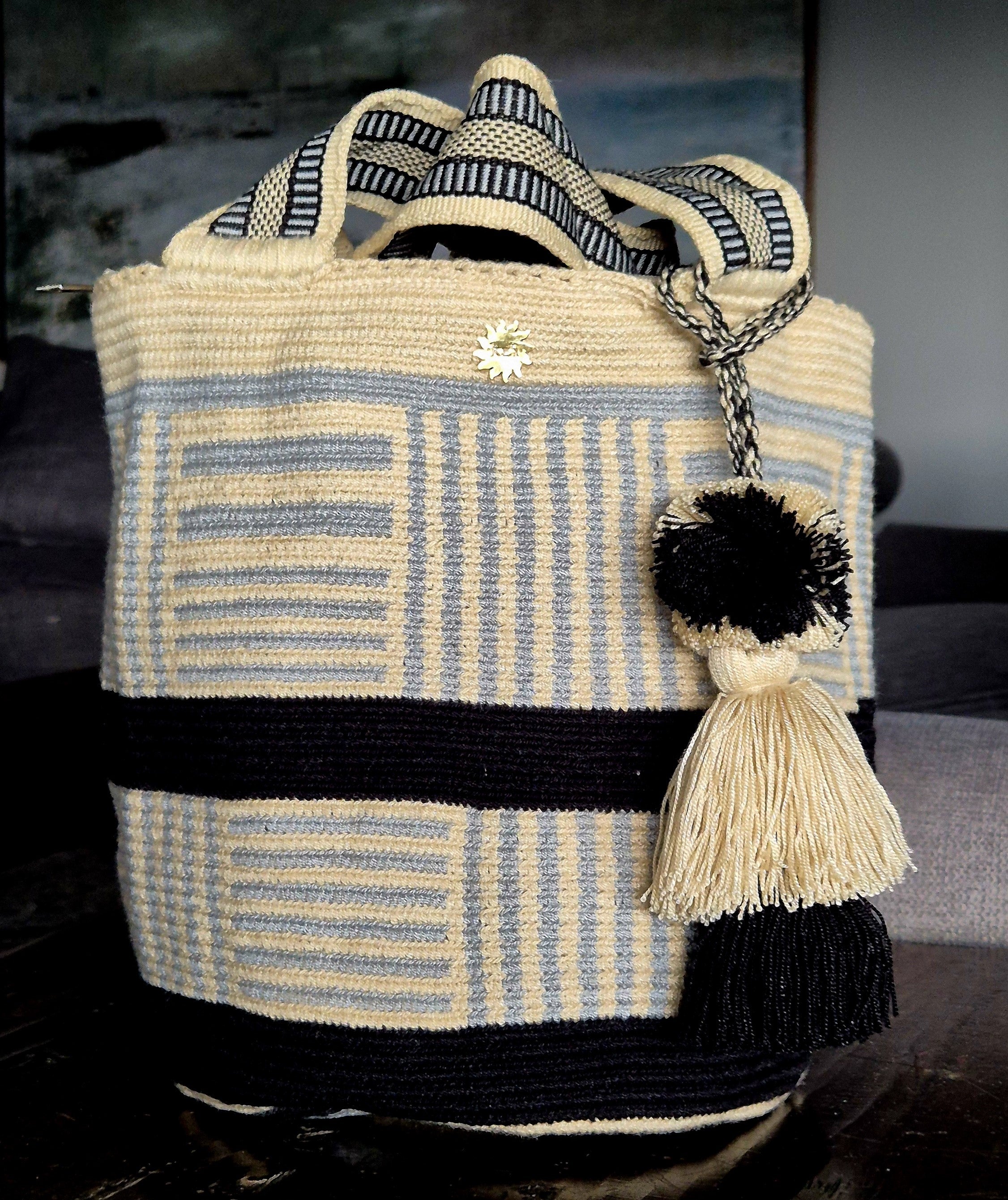 Beige handbag with a horizontal black band and interspersed areas of light blue horizontal and vertical stripes