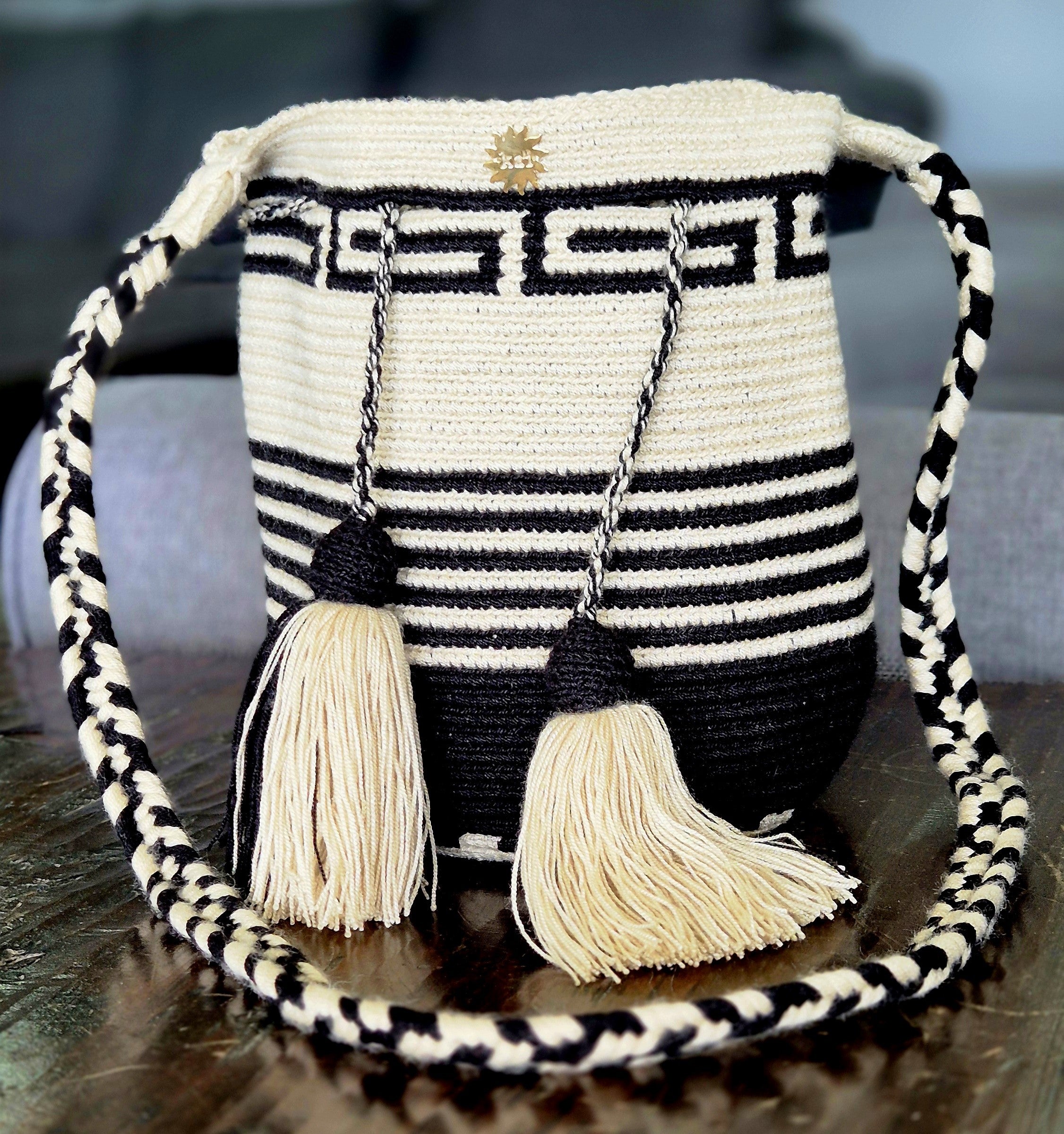 Beige bag with a pattern of black G's or S's on top, black horizontal lines in the middle, and a black base.