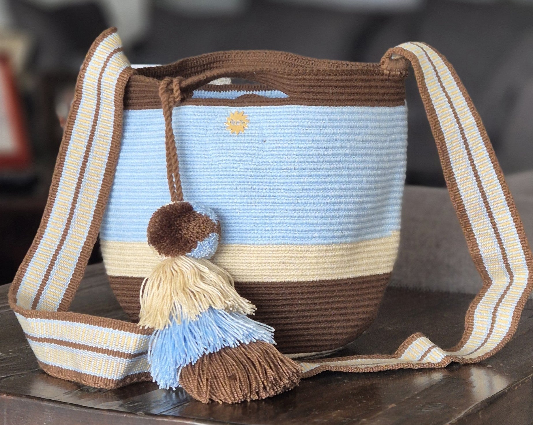 Brown, light blue and beige striped wallet with handle and pompom in matching colors