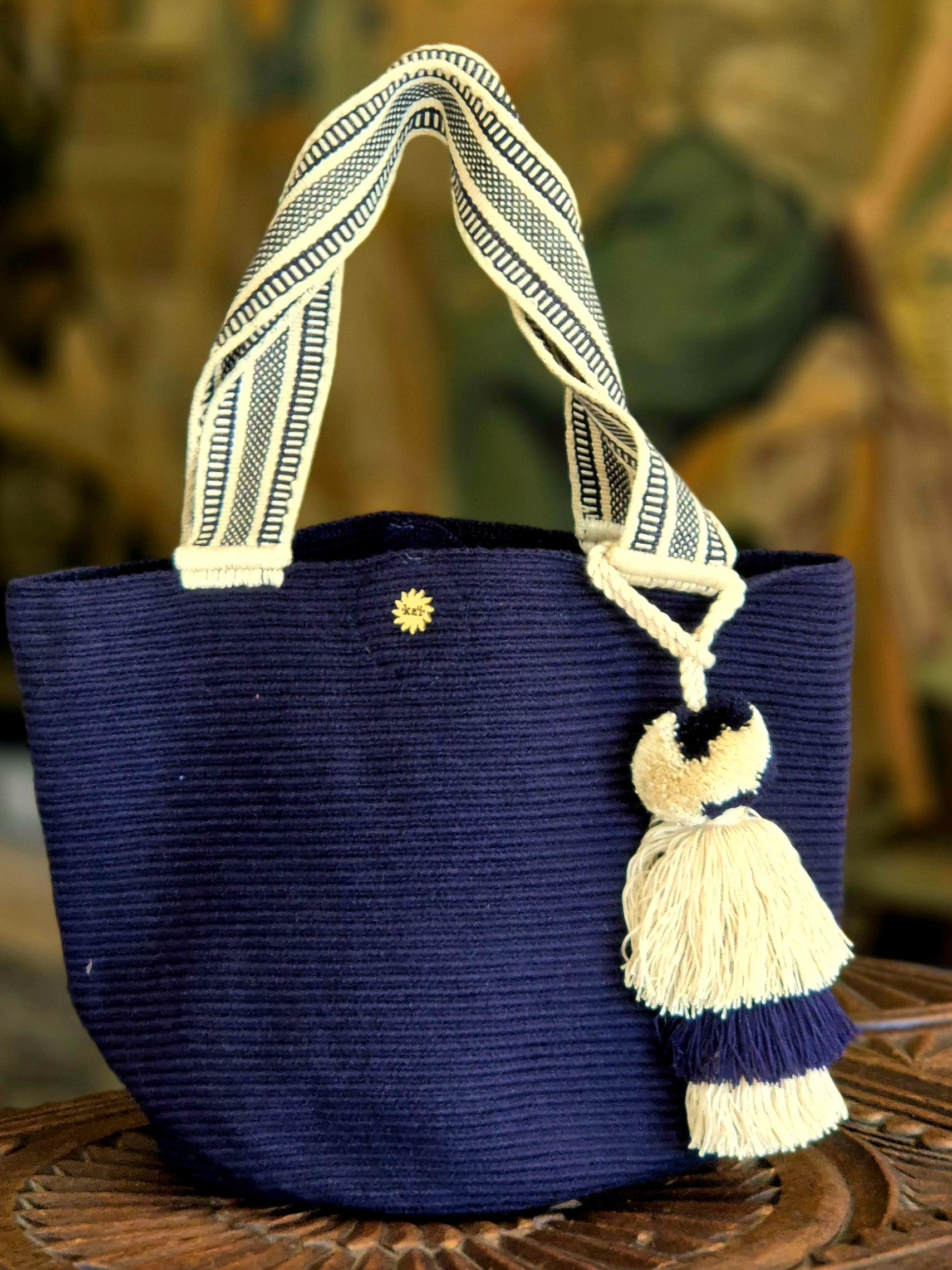 Navy blue handbag with handle and beige and blue pompom