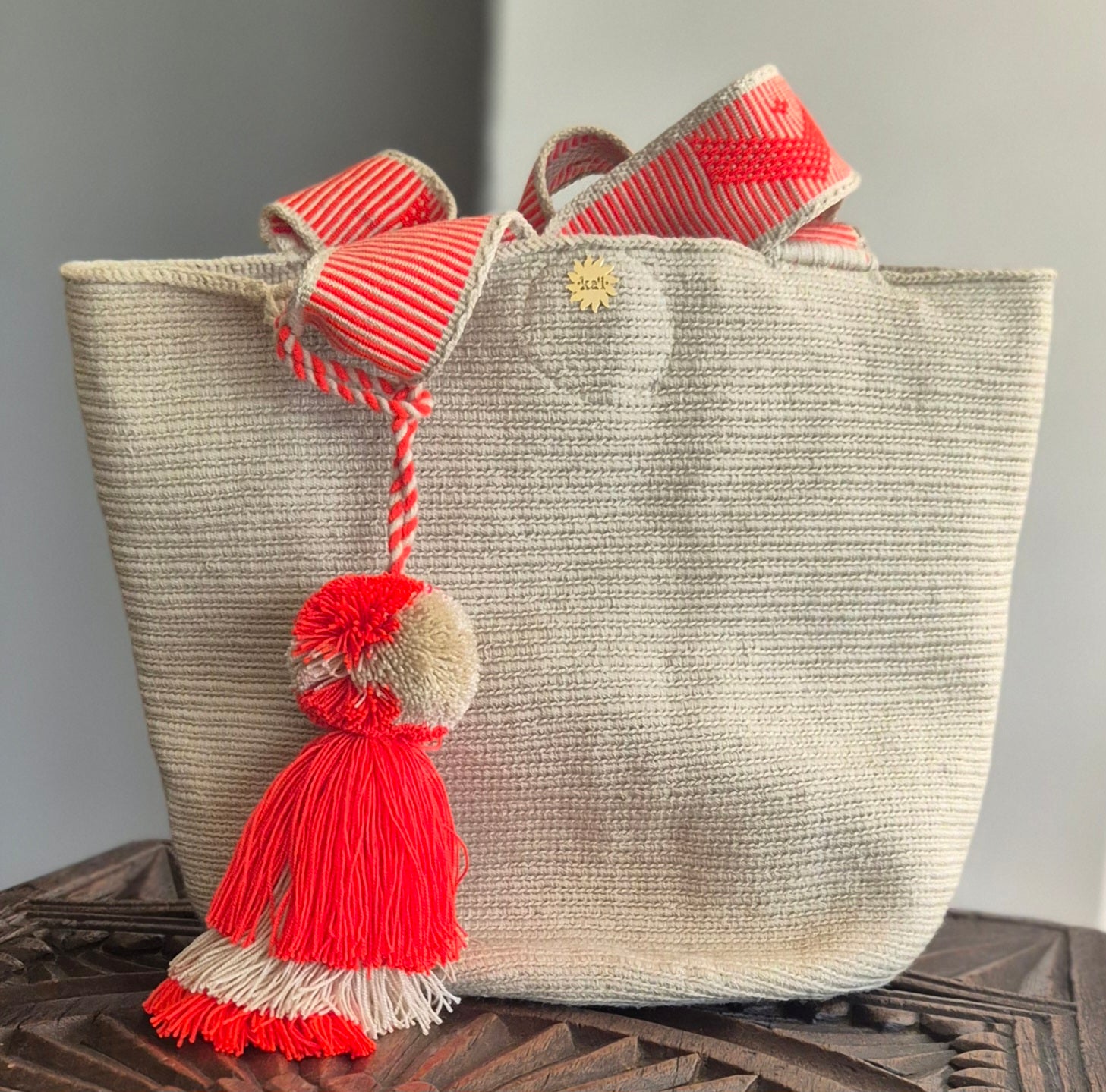 Beige handbag with handle and orange and beige pompom